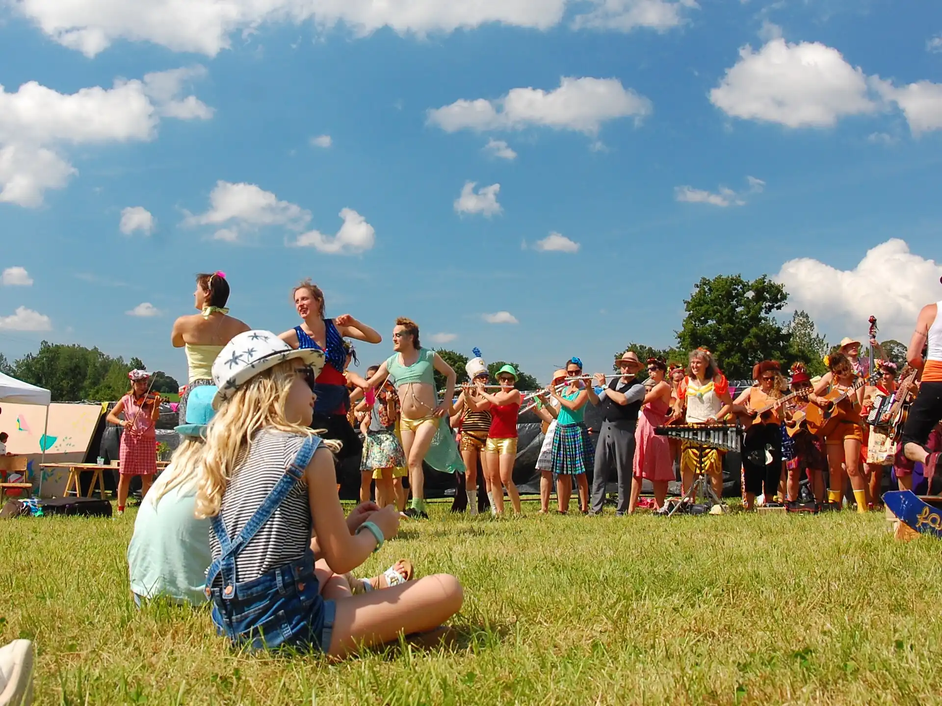 Des enfants regardent un groupe de musique et les personnes qui dansent en plein air