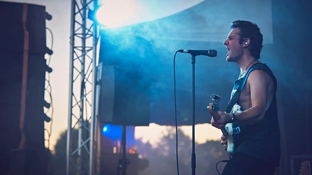 Un chanteur avec sa guitare sur scène au festival au pré du son