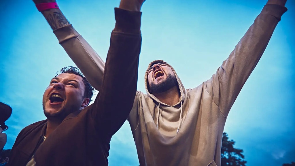 Deux festivaliers chantent devant la scene du festival au pré du son