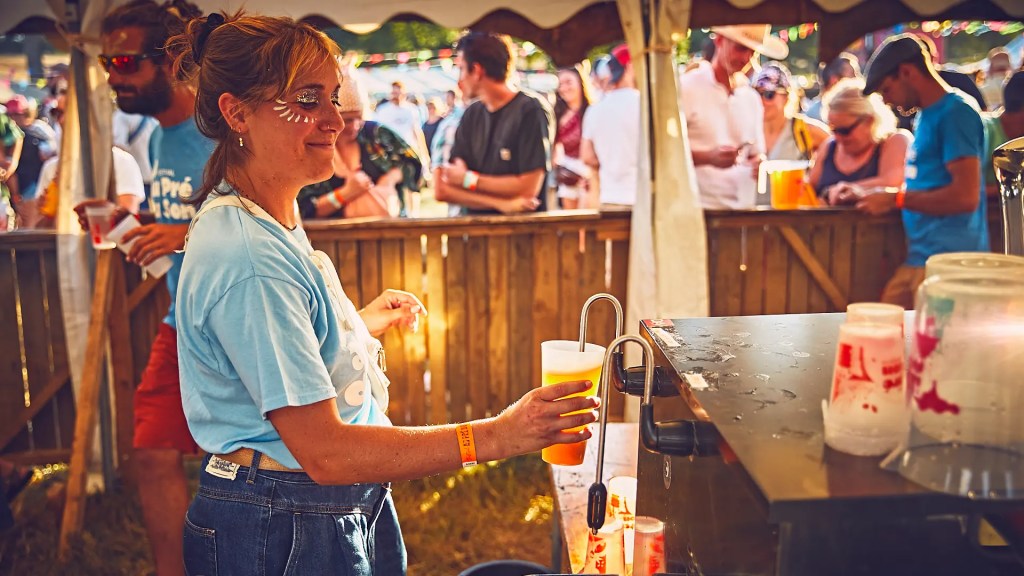 Une bénévole sert de la biere lors du festival au pré du son